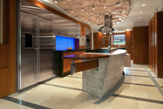 A cast-concrete island with a fold-down leaf made of bubinga  is the focal point of the room. On the curved side of the island is a maple cabinet for storing table linens. The cabinet is wheelchair accessible. 