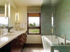 As in the master, the bathing area in the children's bath is defined by ceramic tile in a running bond pattern. The transparent shower surround occupies little apparent space, virtually disappearing against the darker tile.