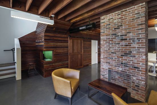 The house’s framing reappears as interior wall framing, finishes, and furniture. A new ceremonial fireplace is made of brick salvaged from the original fireplace and chimney.
