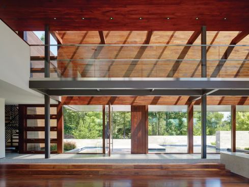 Grand, Custom Home 8,001 to 12,000 square feet. Builder: Lencioni Construction. Architect: Swatt | Miers Architects.

The two-story great room, paneled in African mahogany, contrasts with the white stucco wings.  It serves as the center of the home and opens out to an expansive outdoor space that includes a swimming pool.