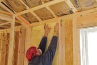 To insulate effectively, fiberglass batts need to fill the entire stud bay without being compressed. To insulate a wall, start by filling the full-width bays. Insert the batt from the top down, pushing it up against the wall plates. If the sides snag on rough lumber, run a putty knife along the side of the stud.