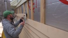 A carpenter installs a clapboard over a ventilated airspace on a wall in Maine.