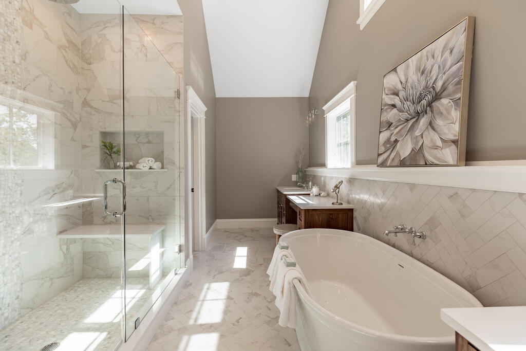 The primary bathroom in this Reading, Massachusetts, home features ample cabinet and counter space, complete with a vanity area and his and hers sinks. The property was designed by Ernest V. DeMaio at Tektoniks Architects and built by MBA Builders.