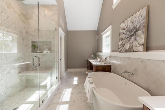 The primary bathroom in this Reading, Massachusetts, home features ample cabinet and counter space, complete with a vanity area and his and hers sinks. The property was designed by Ernest V. DeMaio at Tektoniks Architects and built by MBA Builders.