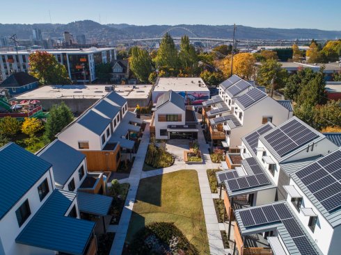 The 16-unit community achieves net-zero energy through a combination of energy-efficient building practices and an 82-kilowatt rooftop solar array.