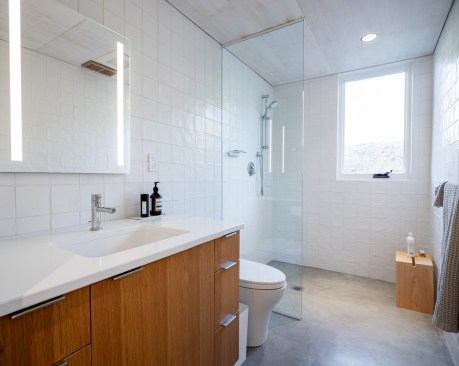 Concrete floors continue to the modern bathroom with a zero-threshold shower, toilet, and vanity sink.