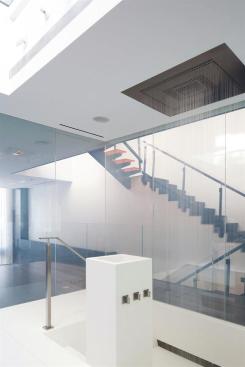 The+privacy+glass+wall+system+is+coupled+with+sleek+design+details+like+an+inset+rain+shower+head+and+a+recessed+tub+with+steps+leading+down.+