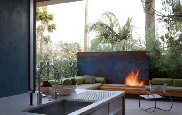 A sliding glass wall system allows the kitchen to become an indoor/outdoor room. A plate of cold-rolled steel serves as a backdrop for the patio's gas fireplace. Interior elements deploy materials-Corian, stainless steel, and teak-in broad, simple forms.