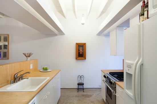 The kitchen floats between two counters with top cabinets framing views through the garage as well as buffering the inside from curious passersby.