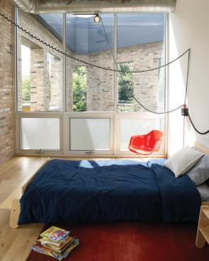 A bedroom overlooks the atrium, with floor-to-ceiling windows that let light in but also maintain privacy.  