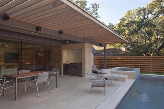 Materials used inside can extend to the exteior, forging inside-out connections. Here, the pool patio is shaded by a generous overhang.The grill is built into an alcove, near a fridge and prep space. 
Project:&nbsp;Chimney Corners, Austin, Texas; Builder: Melde Specialty Construction, Horseshoe Bay, Texas; Architect: Webber + Studio, Austin