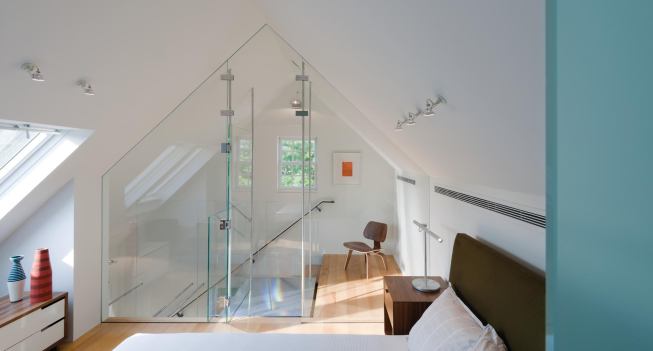 Under the gable roof, a glass wall funnels light down through the old house.