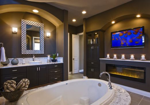 Set into a pedestal lined with Carrara marble tile, this Jacuzzi tub faces a fireplace and built-in cabinets with a TV; on the opposite wall are twin showers. Architect: Jimmy Jacobs; Builder: Jimmy Jacobs Custom Homes