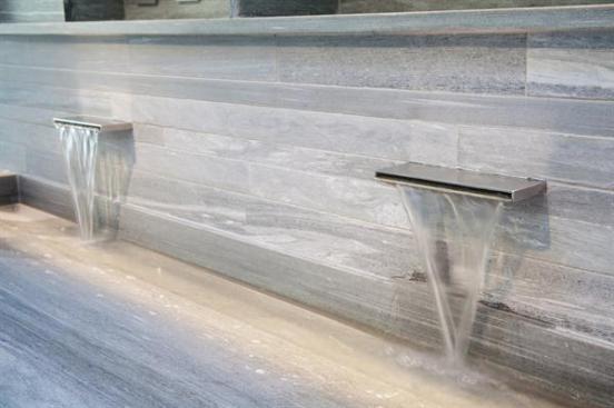Above+the+wide+trough+sink+and+embedded+in+the+stone+wall+are+twin+waterfall+faucets.