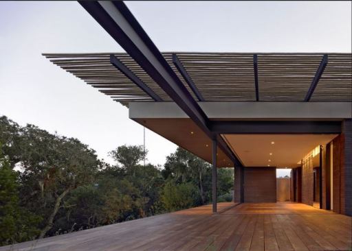 A floating reclaimed teak deck extends the interior when the south and east facades retract into the walls. The lodgepole pine trellis, a waste material, provides shade and helps the building blend with the trees and scrub.