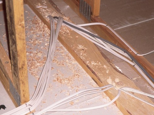 Partition wall plates are a big leak point at the attic floor plane. Drilled holes for wires make the problem worse.