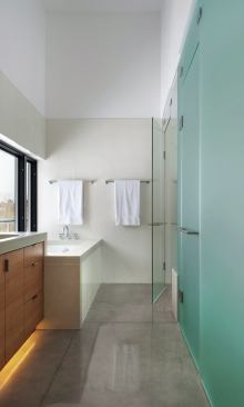 The concrete floor extends into the master bathroom to form an integral shower pan. Glass tile forms the tub skirt.