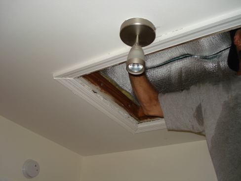 A contractor from Comfort Insulation installs the finishing touch--an "attic tent"--to help insulate the access door to the space above.