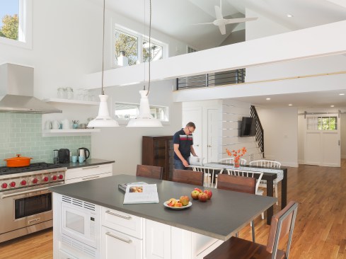 Big windows all around make the room more light-filled and cheerful, as does the use of broad white paint expanses, and a limited material palette.