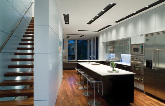 A wedge-shaped cabinet wall provides kitchen pantry storage and support for an open-tread stair.