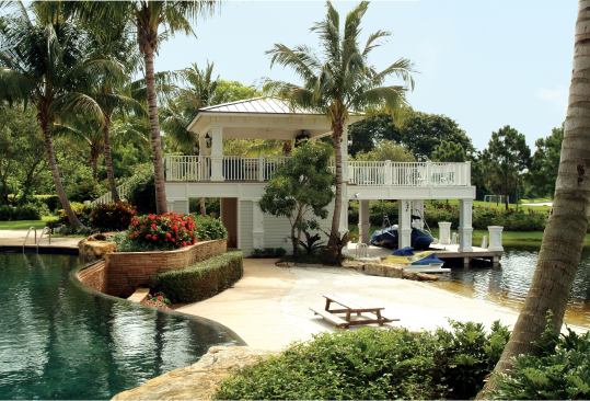 The two-story boathouse houses boats and bathhouse below and a full outdoor kitchen and veranda above.