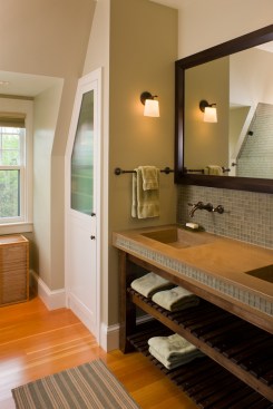 A glass tile backsplash and integral sinks made of concrete add a contemporary touch that makes sense in this shingle-style house.