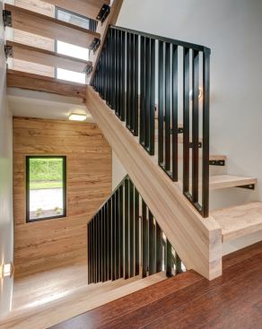Daylight flows through the open stair treads, which were created out of a tree salvaged from the yard.
