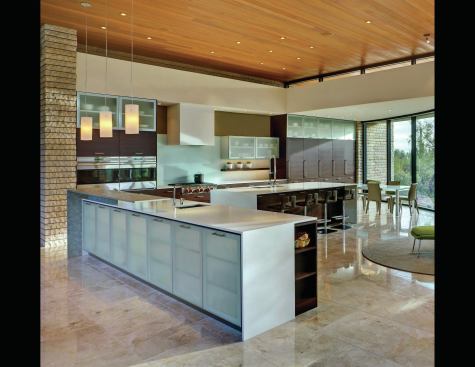 The catering-friendly kitchen consists of two islands—one a bar and buffet, the other a cleaning and prep area—plus a large wall containing storage, refrigeration, and ovens.