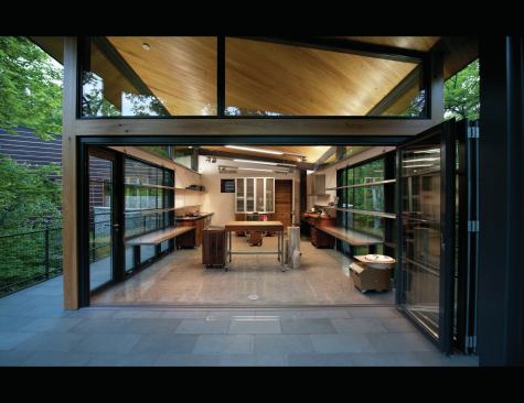 The studio roof is pitched parallel to the house’s roof, matching the slope.