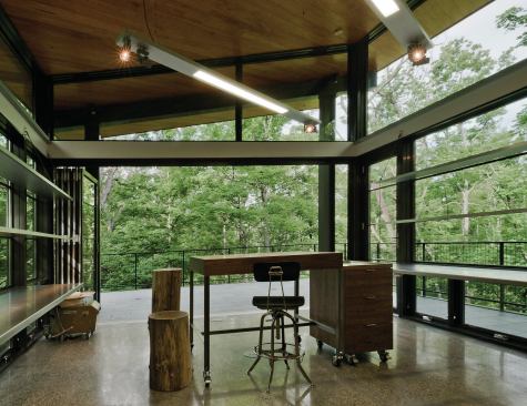 Window divisions, matching the house, become aluminum plate display shelving and stainless steel work surfaces. Exposed steel, cypress siding, Montauk slate, polished concrete, and walnut cabinetry also draw on the house’s material palette.