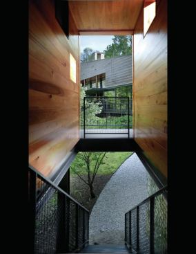 A slot allows a steel stair to drop below the driveway entry and connect with the house's lower level