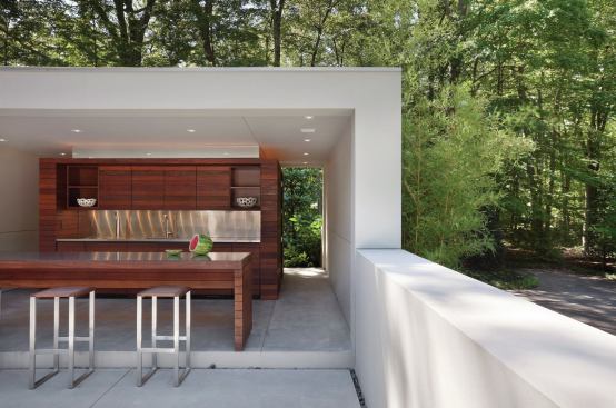 Horizontal ipe panels wrap the kitchen core’s cabinetry and appliances, and a mirror strip at the top lends a sense of floating in the space. Throughout the property, bands of river rock mark transitions and facilitate drainage.