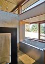 Waterproof plaster veneer gives the walls of the bath texture and random movement. Such visual tricks contrast nicely with the vertical-grain woods Prentiss speced.