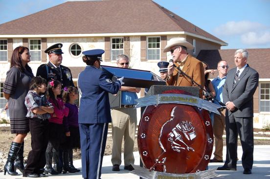 New Lease on Life: Retired U.S. Army Sergeant Jorge DeLeon and his family (left), accepting a new house in San Antonio from Dan Wallrath (center) of Operation Finally Home. DeLeon lost his right leg in a mine explosion in Afghanistan, and his left leg was severely injured. He also received a scholarship from the Texas Sentinels’ Foundation.