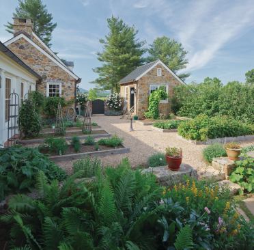 A porch off the kitchen overlooks the vegetable garden, designed by Arentz Landscape Architects. It occupies the void created by the new house and two stone buildings: a potting shed/garden library and a tool shed. Raised beds are made of durable locust wood, and the gravel field provides a clean surface and good drainage. 