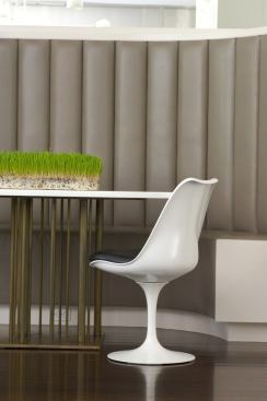 The vertical lines of a custom leather banquette are echoed in the elegantly slim legs of the round breakfast table.