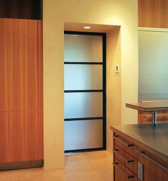 Steel and glass doors bookend the rectilinear room—clear to the exterior view at one end and sandblasted to screen formal dining at the other.
