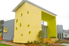 The front elevation of the Sunshower SSIP model serves multiple purposes: On top, it supports a solar panel array; in front, openings give visibility to the structural panels and allow in light and air; and “there’s definitely a playful element” to the design, says architect Judith Kinnard, who adds that the yellow might suggest the sun’s rays.